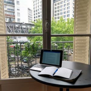 working on laptop next to a window in paris
